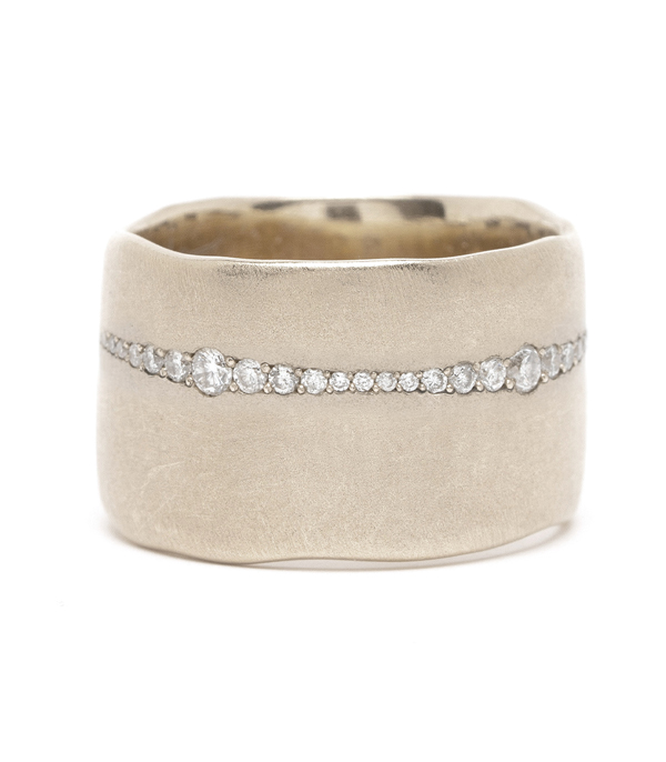 For a bolder look with a touch of glam. This 12mm ultra-wide band sheds an unexpected flash of light with a row of pavé set diamonds. This diamond line gradually tapers and widens as it wraps around the ring, mimicking the paper torn edges of the band. A truly sophisticated and artistic piece!Because of the width of this band, we recommend going up one full size in this ring.Size: 6.5 (TBD) designed by Sofia Kaman handmade in Los Angeles using our SKFJ ethical jewelry process.